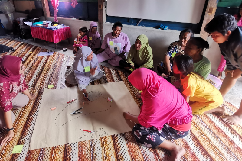 The women from Pulau Tembang draw a map of their island